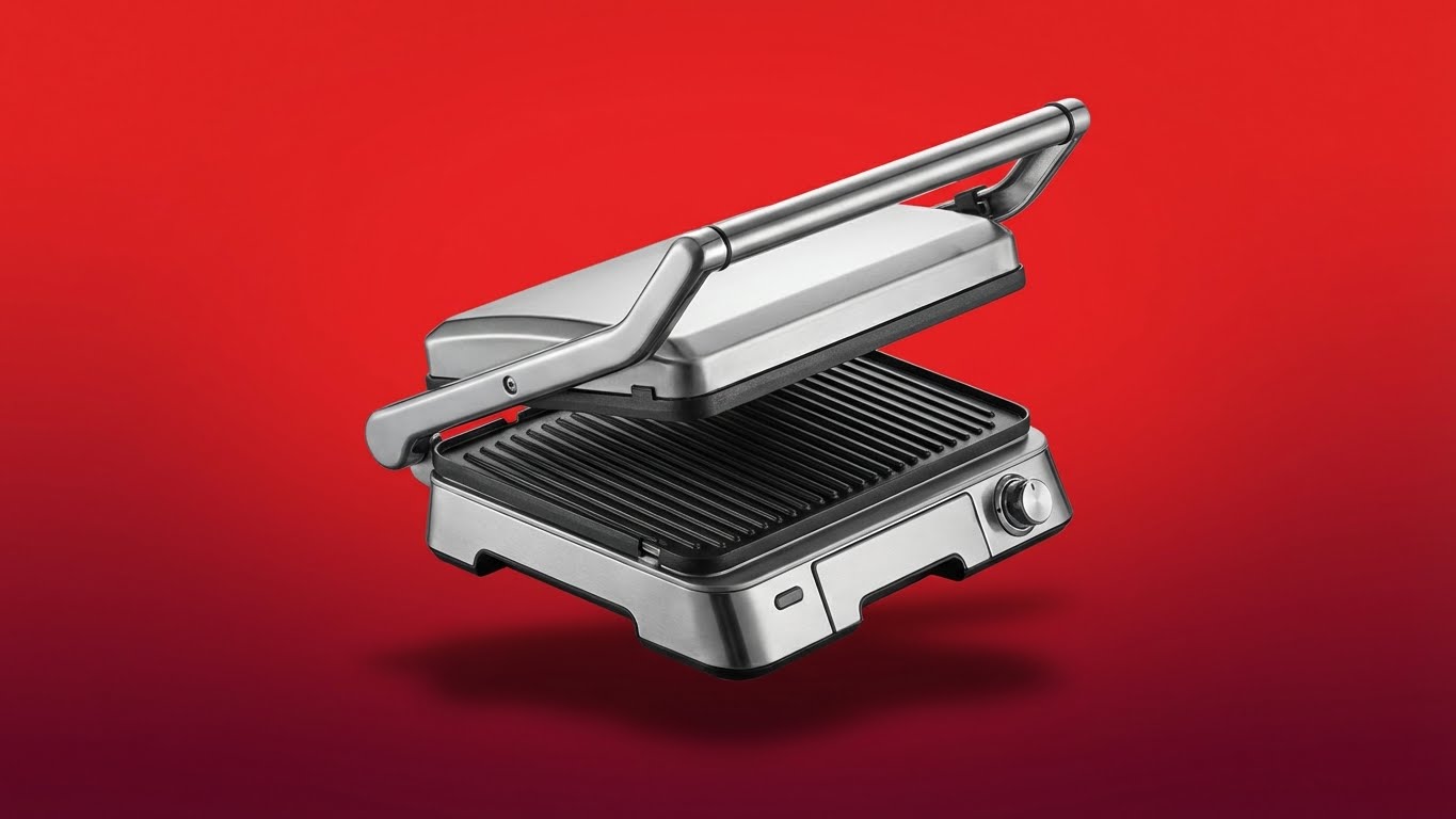 Presse-grill électrique en métal argenté sur fond rouge, plaque de cuisson en relief, image promotionnelle pour les appareils de cuisine